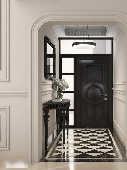 An elegant entryway with a classic black door, intricate floor inlay, and refined wall molding, viewed through a graceful archway.