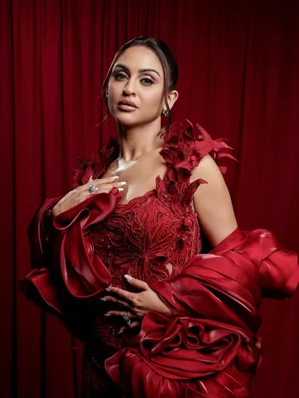 A close-up of the dramatic red gown look. The makeup is kept elegant and defined, with a focus on flawless skin to let the outfit be the hero.