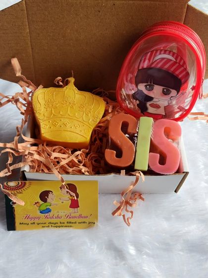 This Rakhi hamper is specially curated for a sister, with 'SIS' alphabet soaps, a crown-shaped soap, and a small pouch.
