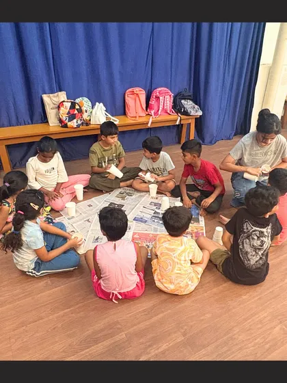A view from behind shows a circle of children completely absorbed in their craft project. Our classes are designed to be engaging, allowing kids to focus and enjoy the creative process.