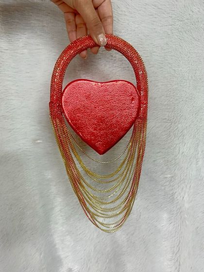 Holding the mini heart fringe bag to show its scale and unique design. The heart-shaped compartment is perfect for essentials, while the fringe adds drama and flair.