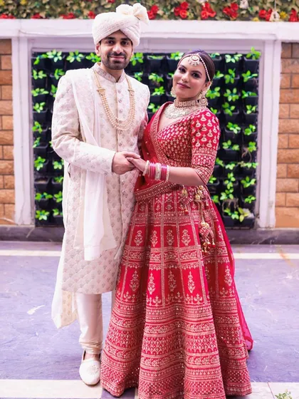 A classic portrait of the bride and groom. Her makeup is timeless and elegant, perfectly suited for her traditional red lehenga and the formal setting.