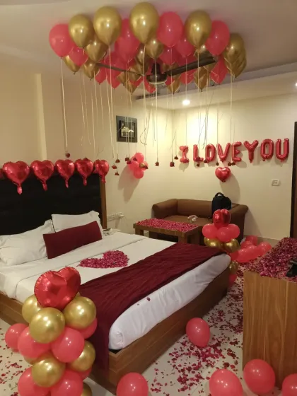 A wide shot of the entire room, showing the scale of the decoration. From the balloon-covered ceiling to the petal-strewn floor, the whole space is transformed.