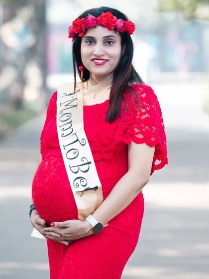 Proudly wearing her "Mom To Be" sash. This portrait in a vibrant red dress is a fun and celebratory way to mark this special milestone.
