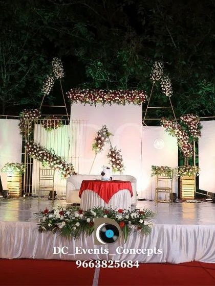 A minimalist yet elegant stage for an outdoor wedding reception. The clean white panels, subtle floral accents, and open design complement the natural surroundings perfectly.