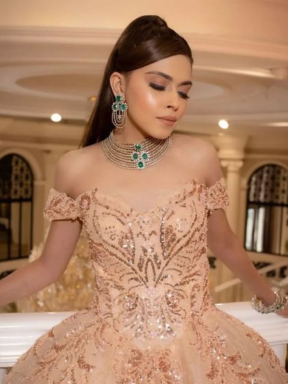 A close-up shot of a client in the peach off-shoulder gown, showcasing her elegant jewelry and the detailed beadwork on the bodice.