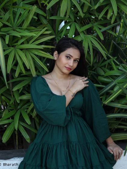 A relaxed and happy outdoor portrait against a wall of green leaves. The natural light is soft and flattering.