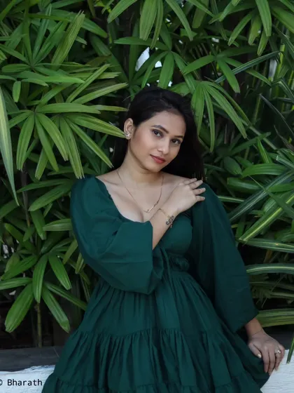 A close-up of the model in the green dress, showing her relaxed pose and the texture of the fabric.