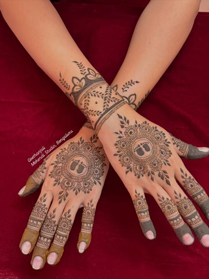The back of the hands for a baby shower celebration, featuring a beautiful mandala with tiny baby feet at the center. A simple yet very meaningful design.