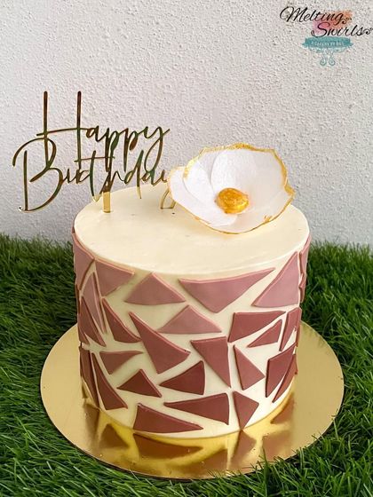 A classy buttercream cake with a mosaic pattern in dusty rose. The design is topped with a delicate wafer paper flower.