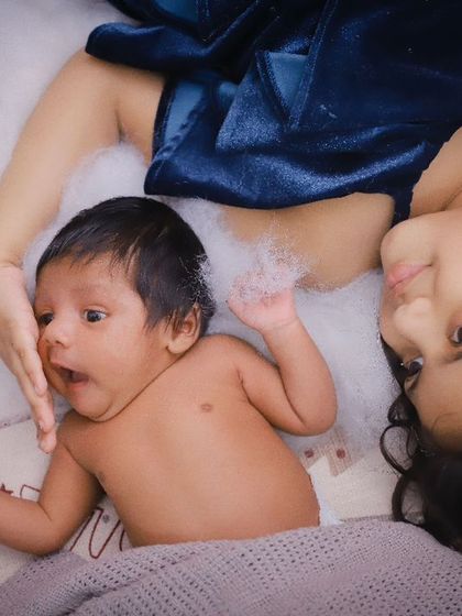 The curiosity and wonder of a new baby. This candid shot captures the newborn's expressive face next to their loving older sister.