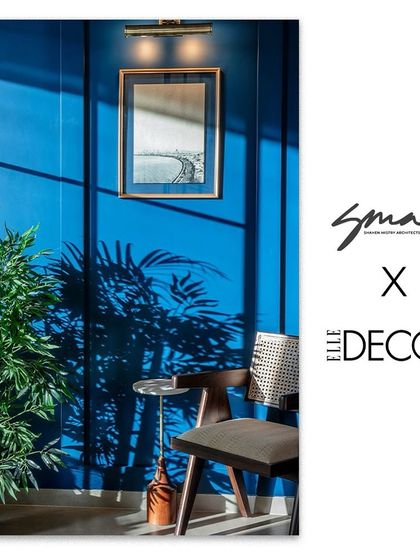 This image, featured by Elle Decor, captures the essence of the office design. The vibrant blue wall, combined with a simple wooden chair and a touch of greenery, creates a space that feels both professional and full of personality.