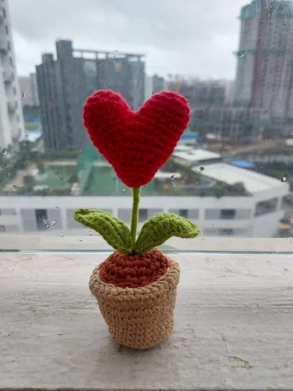 The Heart Pot amigurumi sitting on a windowsill, a lovely piece of handmade decor.