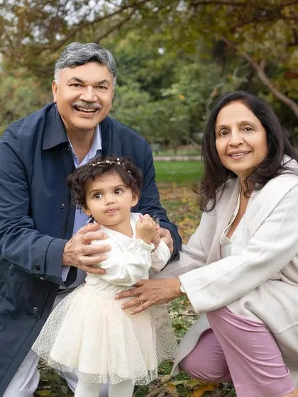 A playful moment between grandparents and their granddaughter amidst the autumn leaves.