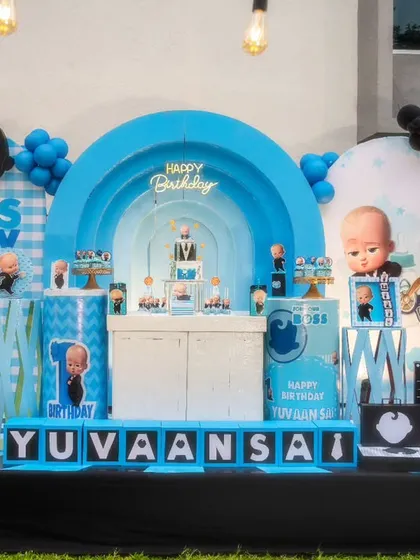 For little boss Yuvaan's first birthday, we went with a sharp and modern 'Boss Baby' theme. The setup included layered blue backdrops, a light-up arch shaped like a suit, and custom props like a money bag and briefcase to complete the look.