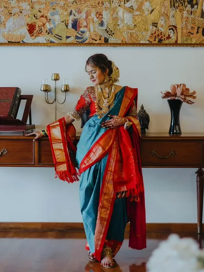 A stunning full-length portrait of a bride in a beautiful blue and red Nauvari saree, showcasing her complete traditional look.