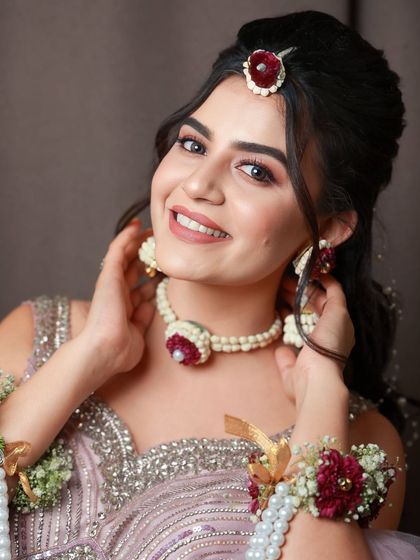 A happy and smiling model showcasing a sangeet look. The makeup is soft and natural, with a focus on her radiant skin.
