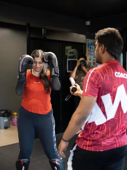 A coach gives one-on-one instruction to a female fighter, correcting her guard and stance. Personalized feedback is key to improvement.
