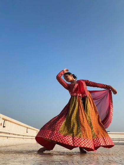 A graceful pose showcasing the beautiful drape and fall of a traditional flared costume, an essential part of the Kathak aesthetic.