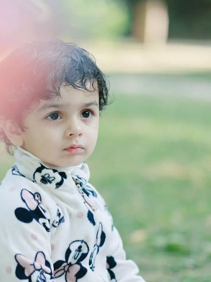 A candid outdoor portrait of a toddler with a thoughtful expression. The soft, natural background helps to frame this moment of quiet contemplation.