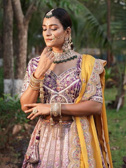 A close-up focusing on the jewellery and the intricate details of the purple blouse.