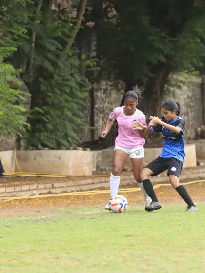 A player in our pink kit skillfully shields the ball from a defender during a match.