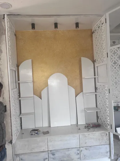 A behind-the-scenes look at the construction of the mandir unit. This image shows the custom shelving and arched details being assembled before the final finishes are applied.