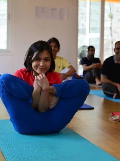 A student smiles while holding Garbhasana, the fetus pose. The TTC is a journey of challenge, discovery, and joy.