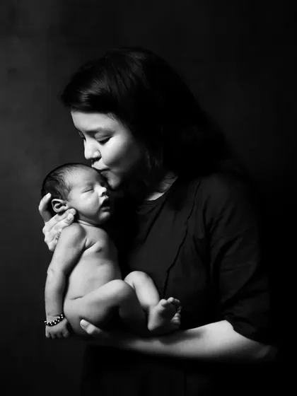 A mother's gentle kiss for her newborn, captured in a timeless black and white portrait. I focus on creating an intimate and comfortable atmosphere to document this incredible bond.