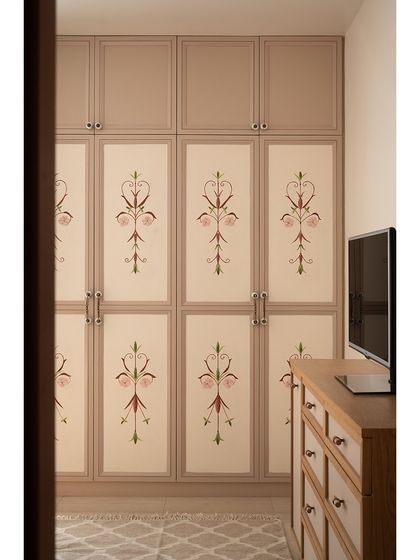 The parents' bedroom wardrobe features beautiful custom hand-painted shutters. The delicate floral motif harmonizes with a mural on the adjacent wall, creating a warm and personal space.