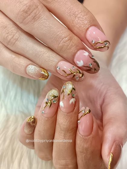 Another view of the luxurious floral set, showing the beautiful combination of nude, gold, and white on elegantly shaped almond nails.