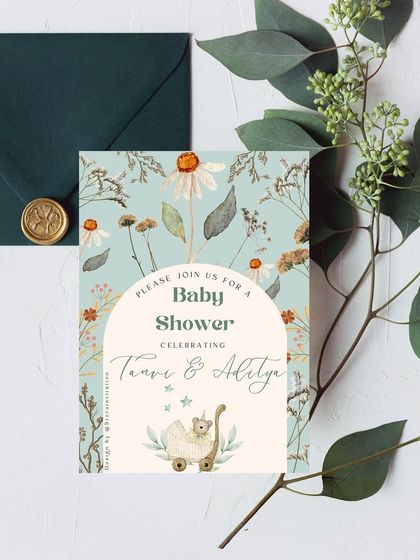 A beautiful and artistic baby shower invitation for actors Tanvi Thakker and Aaditya Kapadia. The design features a lovely arch surrounded by daisies and dried wildflowers for a bohemian and chic feel.