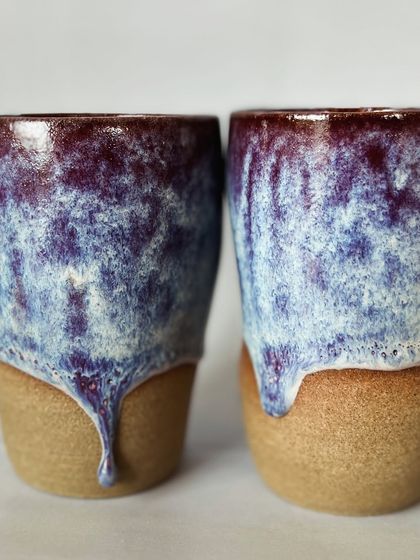 A detail shot of the beautiful, reactive glaze on these grip tumblers. The combination of purple, blue, and white creates a cosmic, dreamy effect.