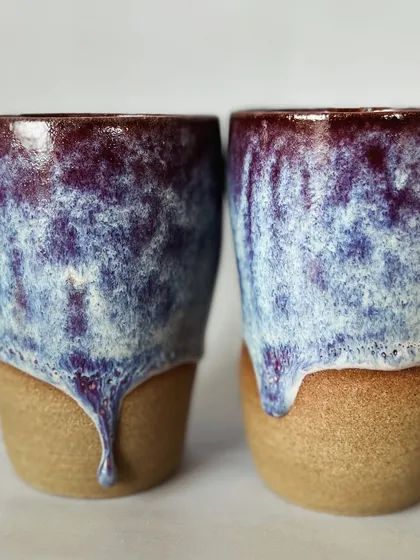 A detail shot of the beautiful, reactive glaze on these grip tumblers. The combination of purple, blue, and white creates a cosmic, dreamy effect.