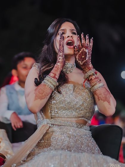 A candid, expressive shot of the bride at her sangeet, with the rich color of her mehndi on full display.