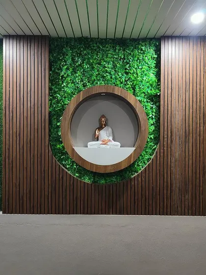 A serene meditation nook featuring a Buddha statue set against a backdrop of vertical garden panels and wooden fluting. This tranquil corner is designed to be a peaceful escape within the home.