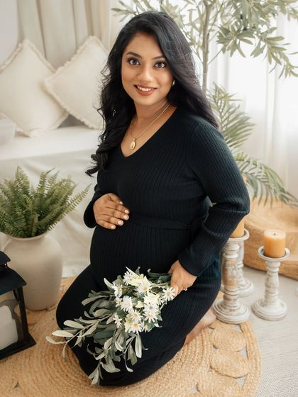 A portrait of pure radiance. Holding a simple bouquet of flowers, this mother-to-be is captured in the warm, inviting atmosphere of my boho-themed studio setup.