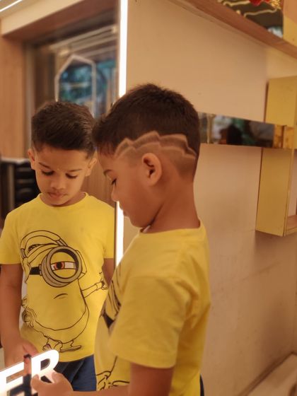 A little gent looking sharp with his new haircut, complete with a cool design, proving that style is for all ages.