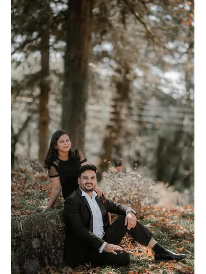 A relaxed portrait of a couple sitting in a forest clearing covered in autumn leaves, perfectly capturing the mood of the season.