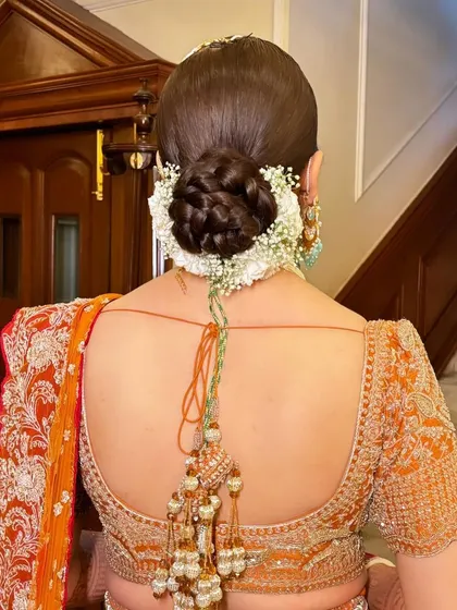 A close-up of this beautiful braided bun, adorned with fresh baby's breath. A classic and elegant choice for any bride.