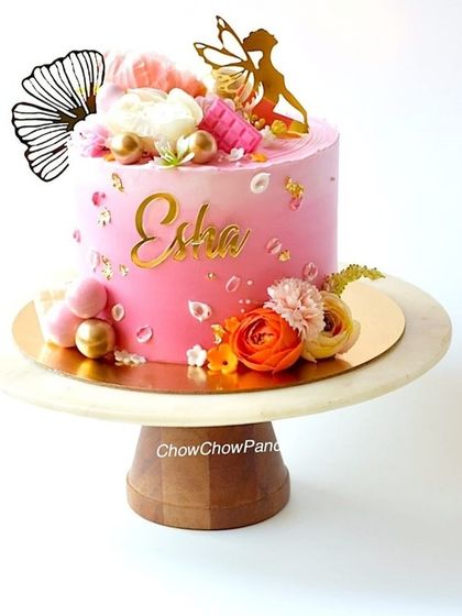 A pretty angel-themed cake with a pink ombre effect. I decorated this vanilla cake with a gold angel topper, delicate flowers, and gold accents for a heavenly look.