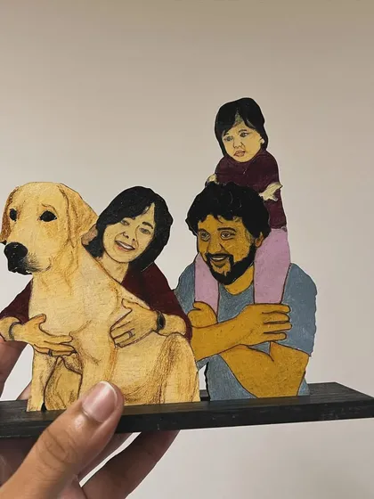 Your family, including your furry friends, can be turned into a beautiful wooden miniature. This custom illustration captures a precious family moment with their daughter and beloved dog, creating a perfect keepsake for a desk or shelf.