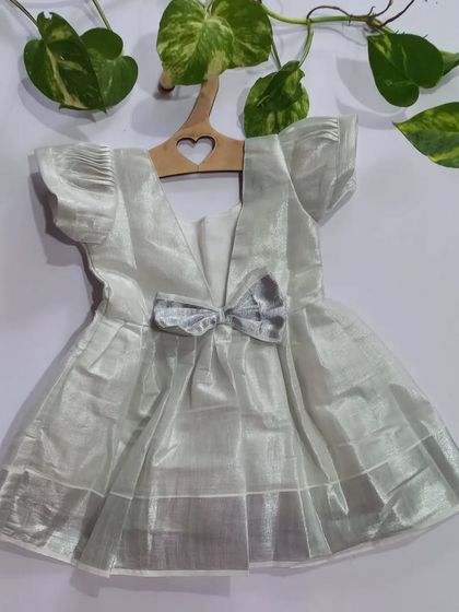 A back view of the silver tissue dress, showing the sweet bow detail. It’s these little touches that make an outfit special, while the cotton lining ensures it's always comfortable.