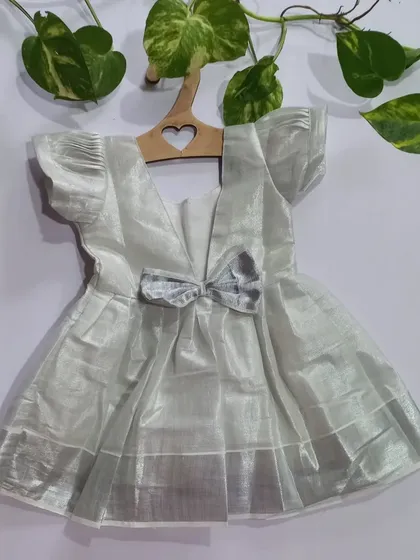 A back view of the silver tissue dress, showing the sweet bow detail. It’s these little touches that make an outfit special, while the cotton lining ensures it's always comfortable.