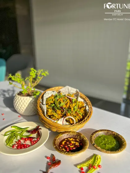 Crispy fried snacks served in a wicker basket, presented with a side of fresh chilies and flavorful dipping sauces.