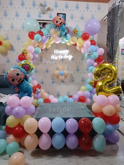 The full Cocomelon birthday setup, showcasing the pastel balloon arch, character foils, neon sign, and light-up number.