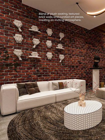 A blend of plush seating, a textured brick wall, and curated art pieces, including a gallery of sculptural faces, creates an inviting and eclectic atmosphere in this lounge.