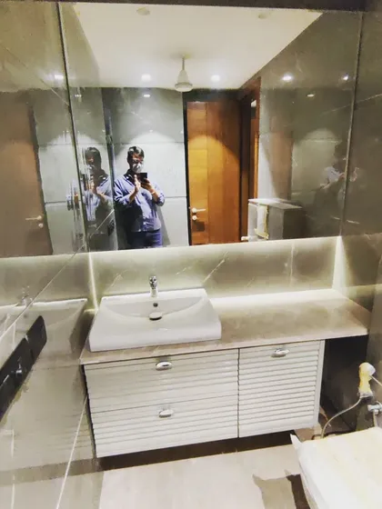 A completed modern bathroom in a GK-1 residence. The design features large-format grey tiles, a floating vanity with ambient lighting, and a large mirror to create a sense of spaciousness.