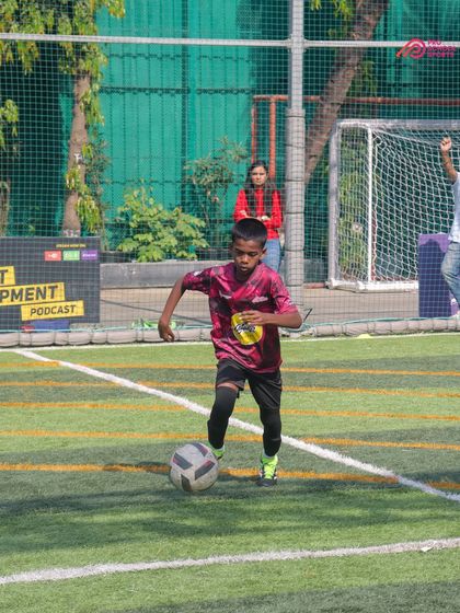 A player dribbles the ball with precision on the turf during a competitive youth league game.