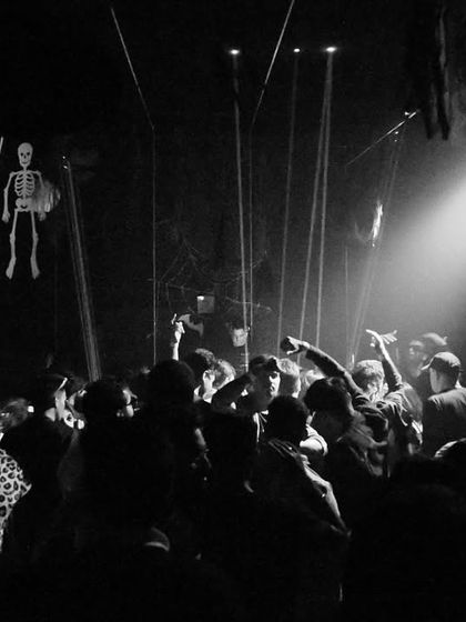 A wider black and white shot of the Insomnia Club, showing the scale of the crowd and the dramatic single-source lighting.